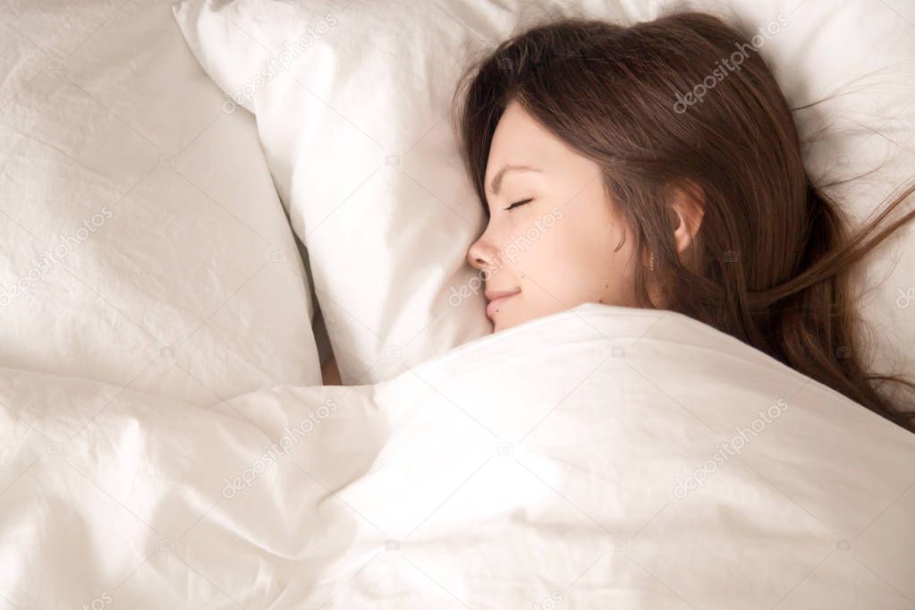 Young woman sleeping well under warm blanket