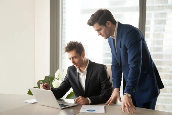 Zwei seriöse Geschäftsleute schauen auf den Laptop-Bildschirm und arbeiten an — Stockfoto