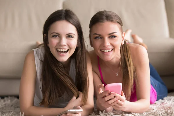 Två unga kvinnor med mobiltelefoner som har roligt online — Stockfoto