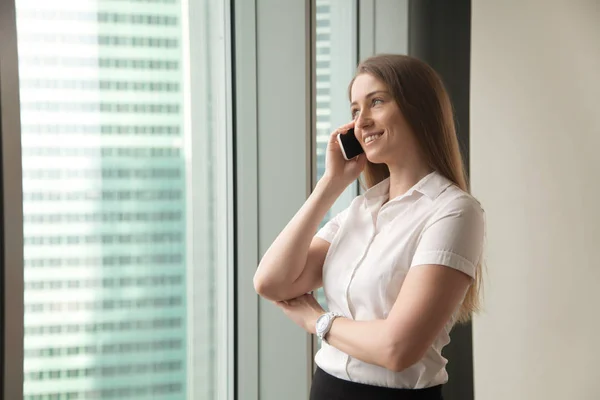 Smiling businesswoman talking on phone in office, making answeri