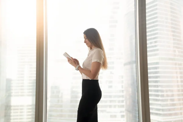 Ocupada mujer de negocios seria usando tableta digital, de pie cerca de b — Foto de Stock