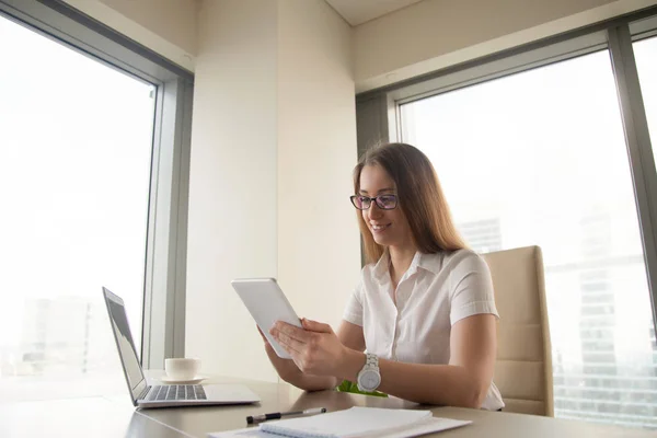 Smilende forretningskvinne med nettbrett sittende på arbeidsplassen – stockfoto