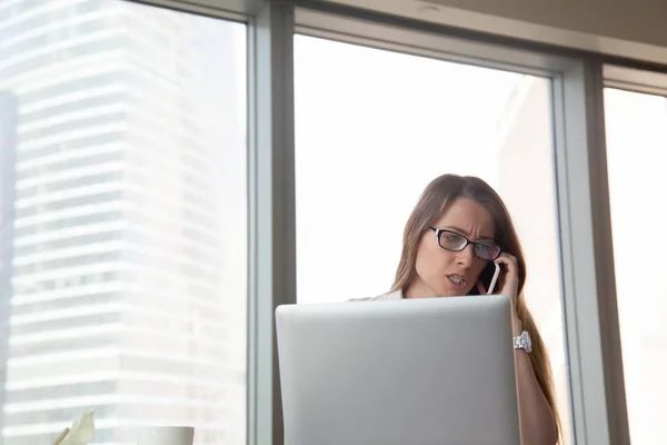 Angry businesswoman talking on mobile at workplace, arguing by c — Stock Photo, Image