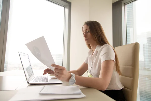 Fokusert forretningskvinne som bruker laptop, analyserer diagrammer, lager pres – stockfoto