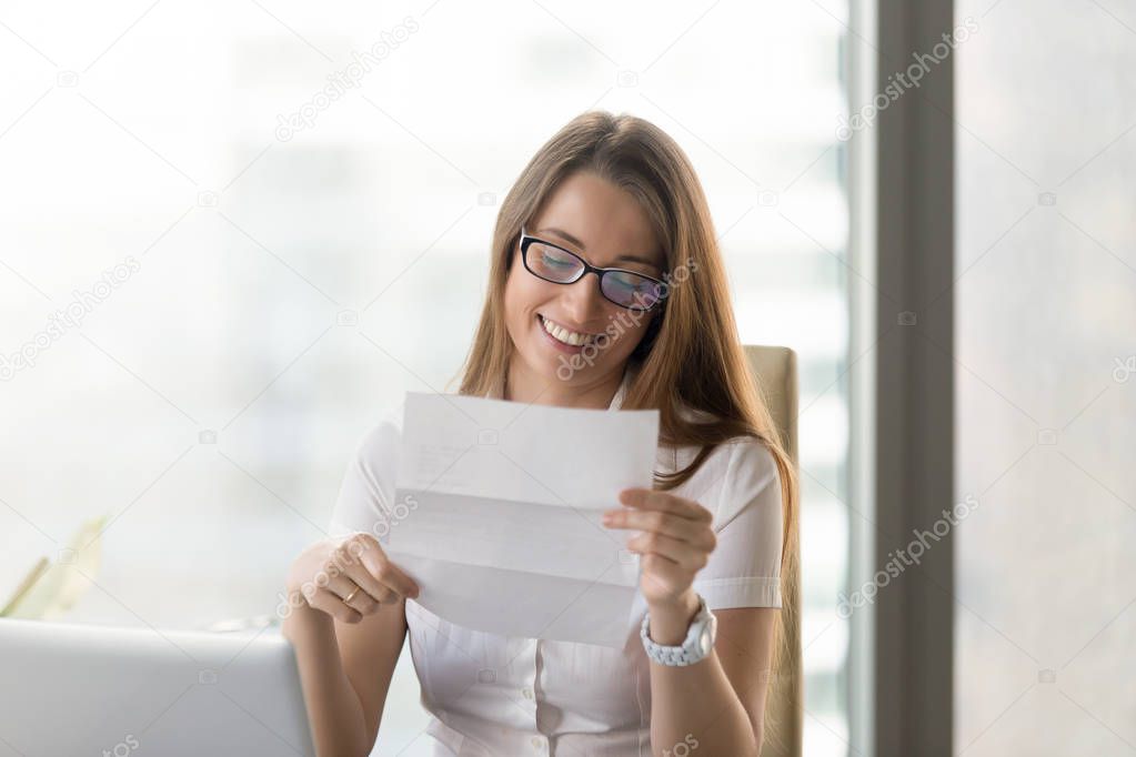 Smiling excited businesswoman reading letter, enjoying positive