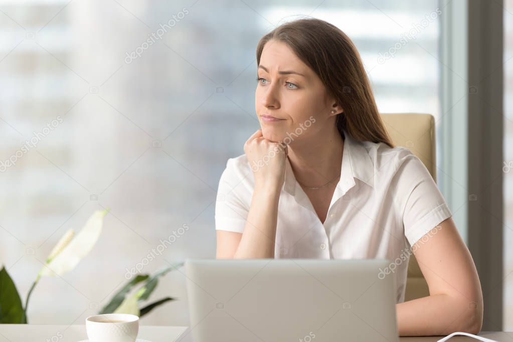 Discontented thoughtful woman holding hand under chin bored at w