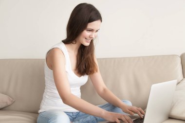 Dizüstü bilgisayar, evden online çalışma kullanan mutlu genç kadın