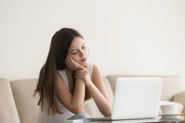 Genç kadın dizüstü bilgisayar ile evde oturan, uykulu hissediyorum bıkkın
