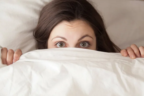 Funny surprised girl covering face with white blanket, headshot — Stock Photo, Image