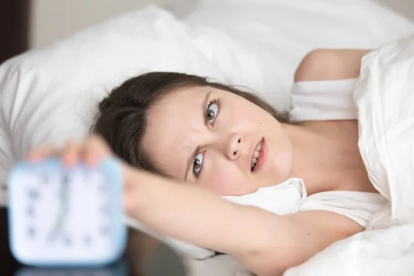 Раздраженная сонная молодая женщина выключает будильник, плохое пробуждение — стоковое фото