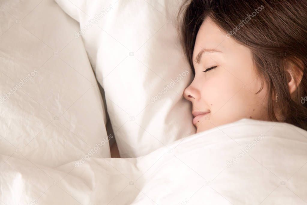 Beautiful woman sleeping in cozy bed, closeup headshot top view