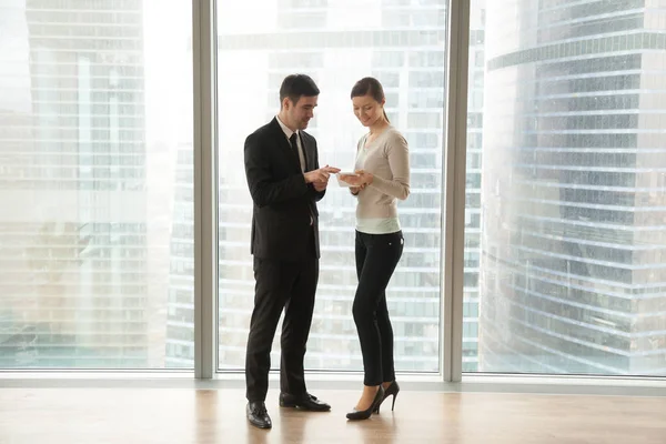 Two employees talking, using digital tablet, standing at big win — Stock Photo, Image