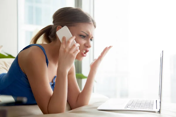 Kvinna som bråkar på mobiltelefon medan du använder laptop — Stockfoto