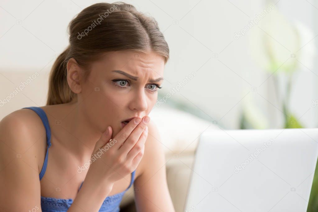 Woman looking on laptop screen with fear