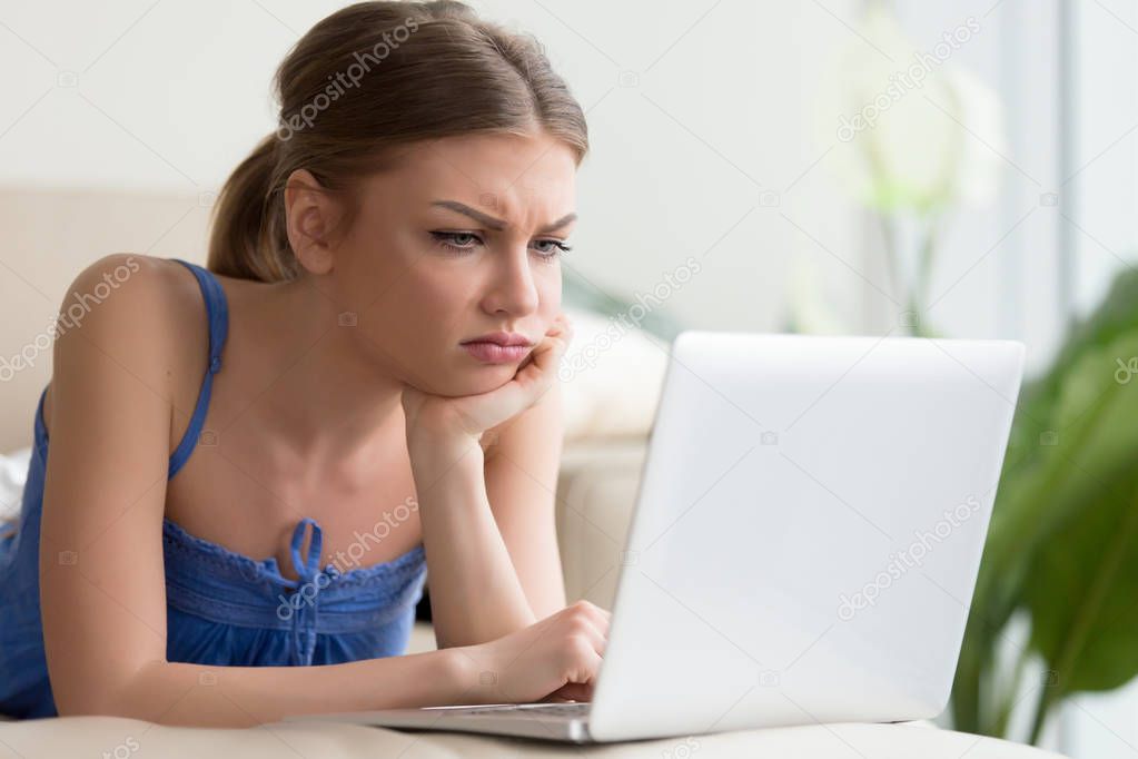 Young woman watching boring movie on laptop
