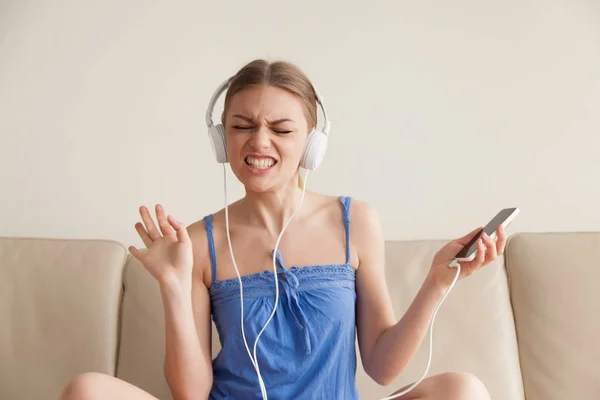 Vrouw in koptelefoon luisteren van muziek vanaf mobiele telefoon — Stockfoto