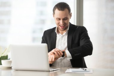 Kol saati kocaman bir gülümseme ile seyir iş yerinde mutlu işadamı.