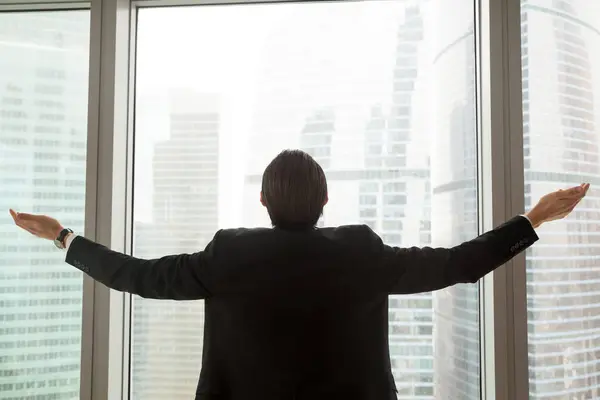 Erfolgreicher Geschäftsmann steht mit Waffen am Bürofenster — Stockfoto