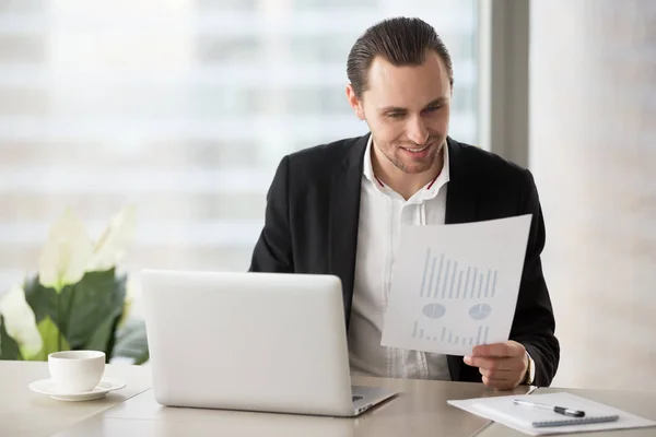 Happy smiling businessman in office looking at financial report — Stock Photo, Image