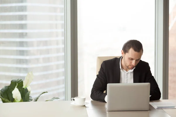 Молодий бізнесмен, що працює на ноутбуці в сучасному офісі . — стокове фото