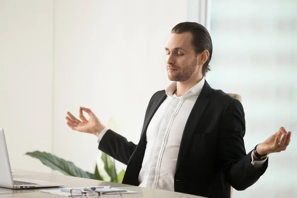 Calma joven hombre de negocios meditando en el lugar de trabajo en la oficina moderna — Foto de Stock