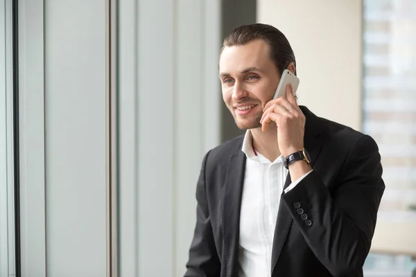 Glimlachend knappe zakenman in pak praten op mobiele telefoon. — Stockfoto