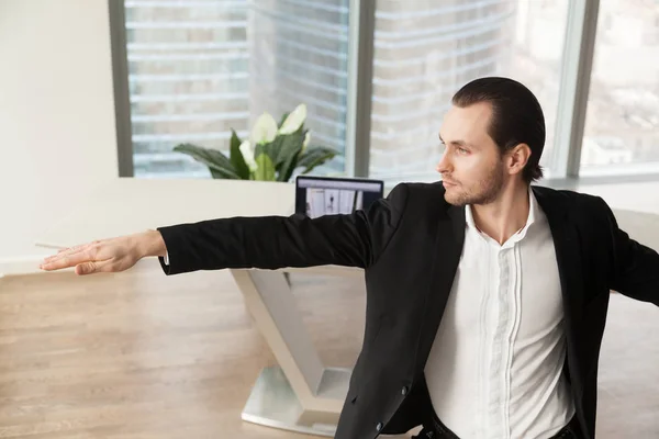 Jonge zakenman doen yoga op werkplek in warrior pose. — Stockfoto