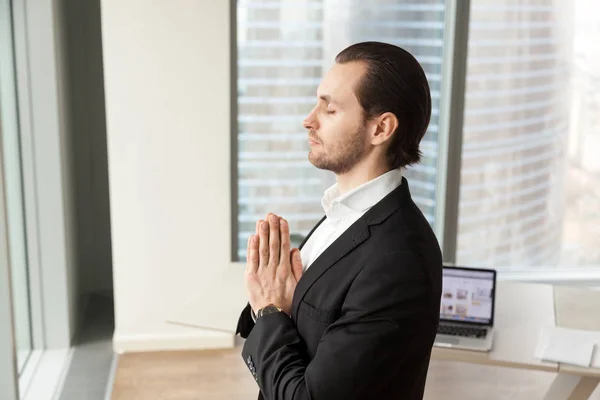 Erfolgreicher Geschäftsmann meditiert am Arbeitsplatz im modernen Büro. — Stockfoto