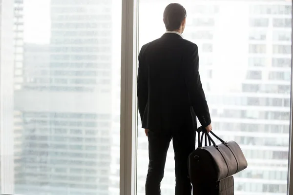 Geschäftsmann mit Gepäck steht vor großem Fenster. — Stockfoto