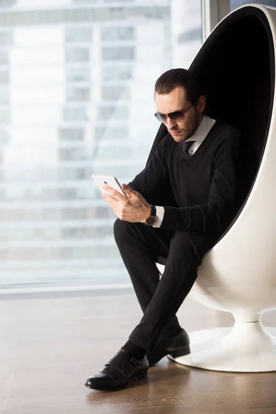 Homme élégant sérieux dans les lunettes de soleil regardant tablette électronique . — Photo