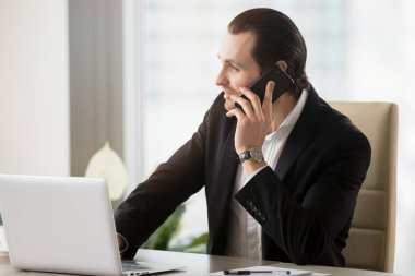 Modern ofis cellpho üzerinde konuşurken gülümseyen yakışıklı işadamı