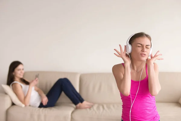 Genç kız müzik dinleme ve kız arkadaşı kanepede rahatlatıcı. — Stok fotoğraf