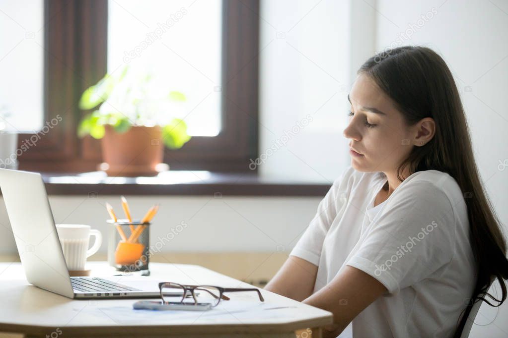 Female employee stretching her back, keeping eyes closed.