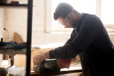 Ciddi yetenekli marangoz ahşap taşlama için zımpara kullanarak çalışma