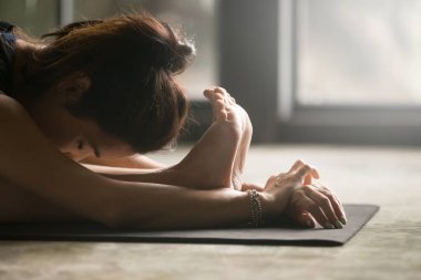 Paschimottanasana genç kadın poz, stüdyo kat arka plan,
