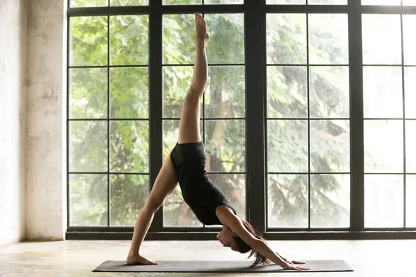 Tek bacaklı aşağı doğru bakan köpek poz genç çekici kadın