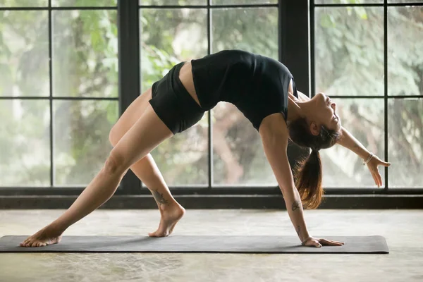 Giovane donna attraente in posa Camatkarasana, sfondo studio — Foto Stock