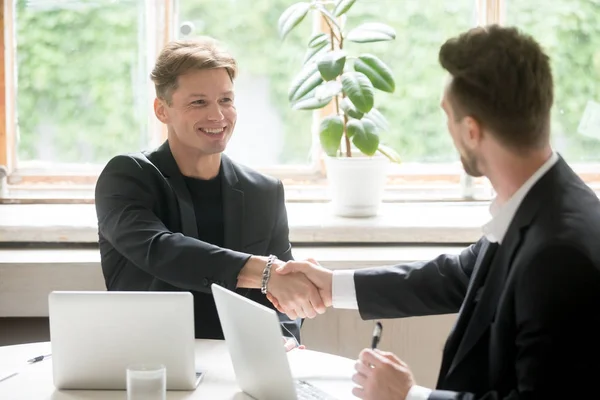 Two young business people shake hands in office. — Stock Photo, Image