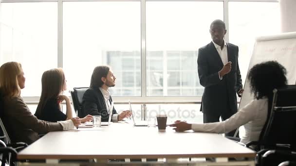 Treinador preto dando apresentação para empresários no escritório com flipchart — Vídeo de Stock