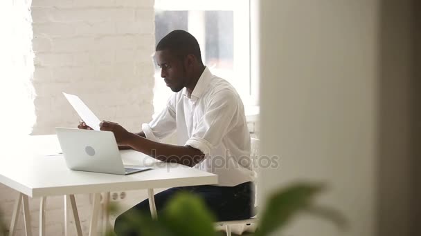 Африканский бизнесмен консультирует клиента, показывая документ с финансовой статистикой — стоковое видео