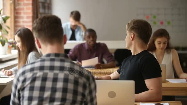 Uomo d'affari che lavora su laptop, che parla con un collega africano nel coworking — Video Stock