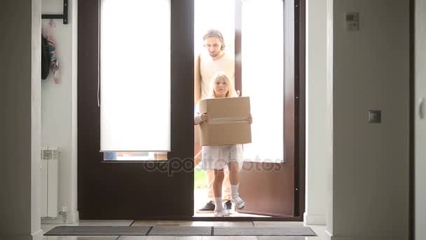 Счастливая семья с детьми, держащими коробки, открывающие дверь в дом — стоковое видео