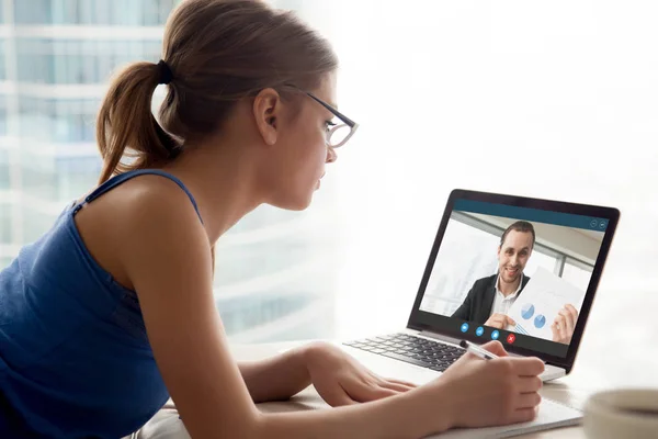 Mujer en gafas viendo webinar de negocios y tomando notas . —  Fotos de Stock