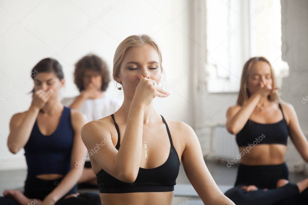 Group of young sporty people making Alternate Nostril Breathing