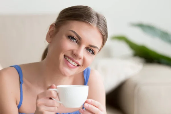 Молодая улыбающаяся привлекательная женщина наслаждается кофе, глядя в камеру — стоковое фото