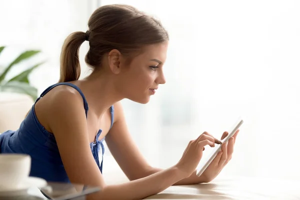 Mujer joven usando tableta digital, leyendo e-book, revisando noticias — Foto de Stock