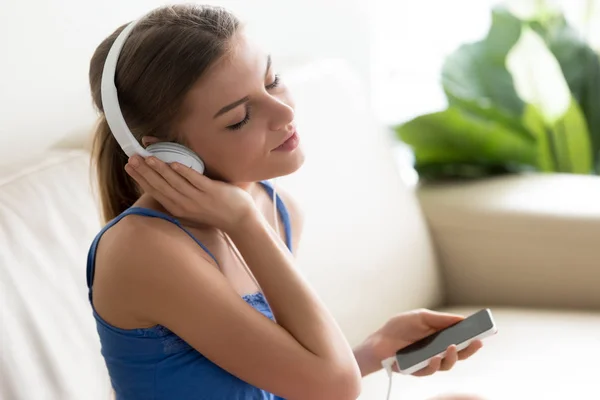 Entspannte junge Frau genießt Musik im Kopfhörer per Handy — Stockfoto