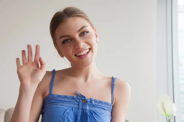Улыбающаяся девушка-подросток машет рукой, глядя на веб-камеру, снимая видео — стоковое фото