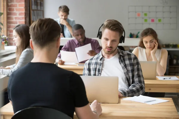 Serious casual entrepreneur in headphones looking at laptop scre — Stock Photo, Image