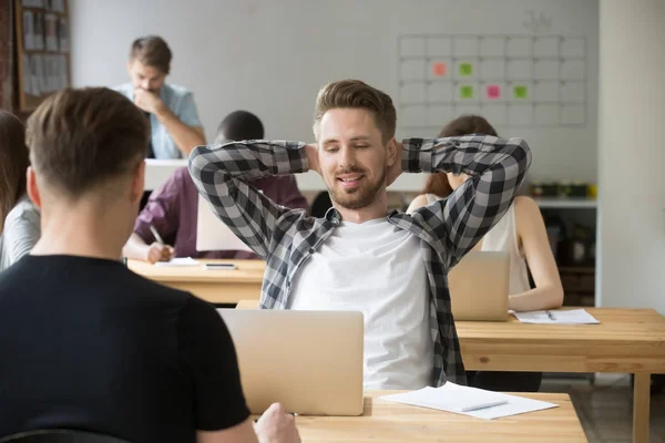 Lächelnder Unternehmer entspannt sich am Arbeitsplatz im gemeinsamen Büro. — Stockfoto